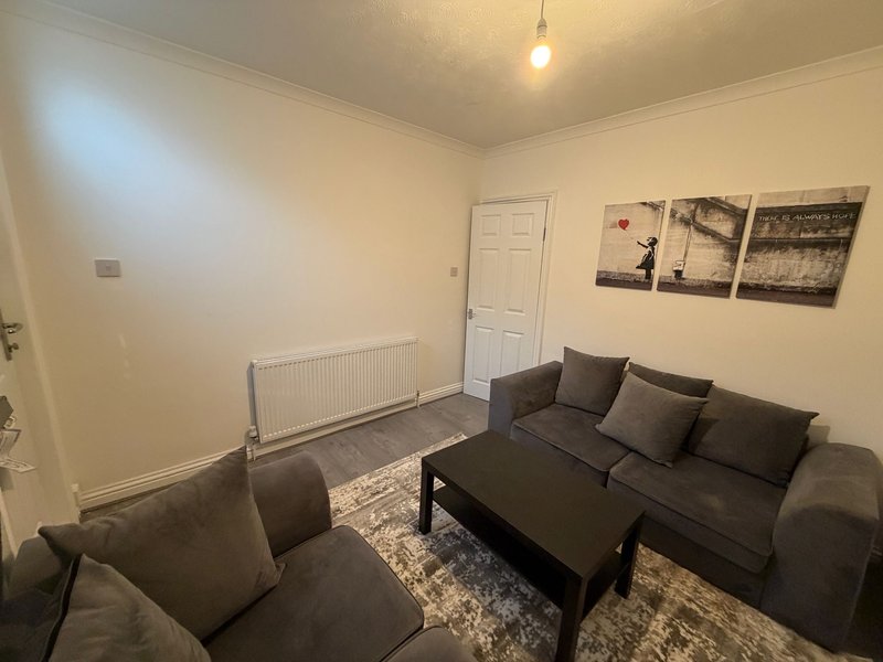 Living room with dark grey sofa, armchair, black coffee table and wall art