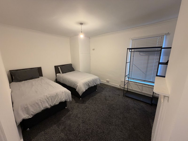 Twin bedroom with two single beds, dark carpet, window with blinds and pendant light