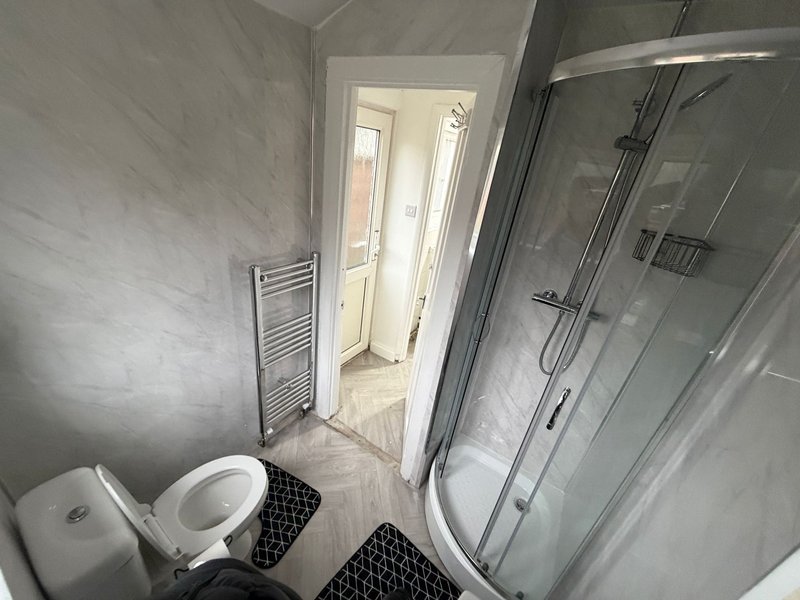 Modern bathroom with toilet, shower enclosure, heated towel rail and grey tile walls