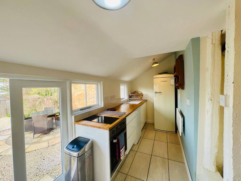 Galley kitchen with white cabinetry, tile flooring, and door to garden patio