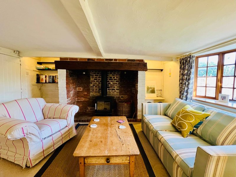 Cozy living room with fireplace, striped sofas, wooden coffee table and bay windows