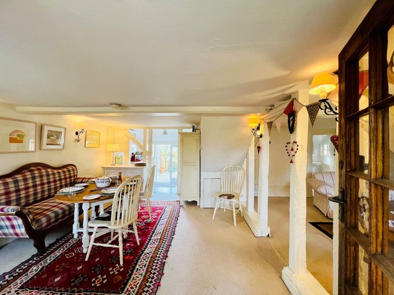 Open-plan living area with seating, dining table, kitchen area and glass doors to garden