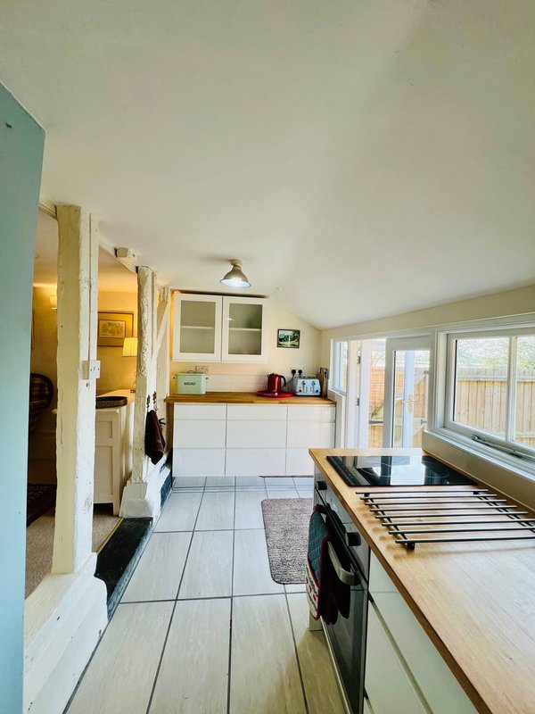 Kitchen with white cabinetry, tile flooring, appliances and glass doors to garden
