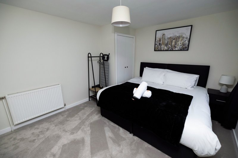 Bedroom with black bed frame, white bedding, pendant light, and wall art