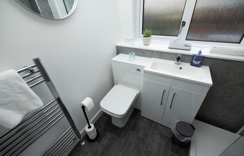Modern bathroom with white vanity, toilet, heated towel rail and window