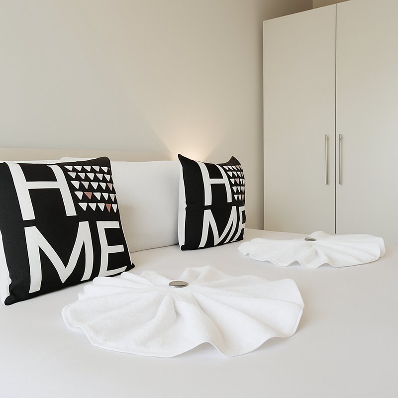 Modern bedroom with white bed, black and white patterned cushions, white wardrobe