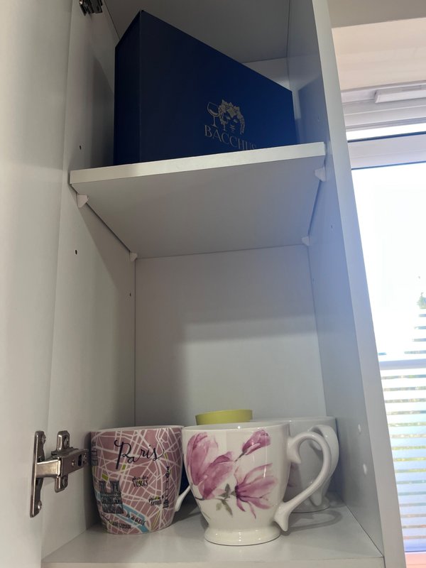 White shelving unit with decorative mugs, pitcher, and boxed items on display
