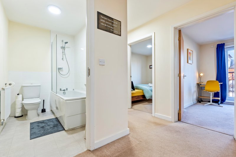 Modern apartment hallway with bathroom entrance, bedroom doorway, and neutral decor throughout