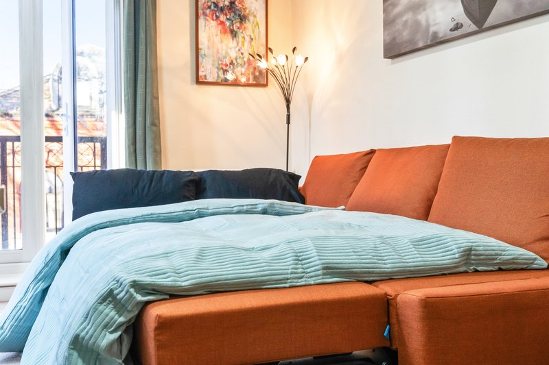 Bedroom with orange upholstered bed, blue bedding, navy cushions, and framed wall art