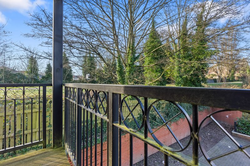 Wooden deck with black metal railing overlooking garden and bare trees