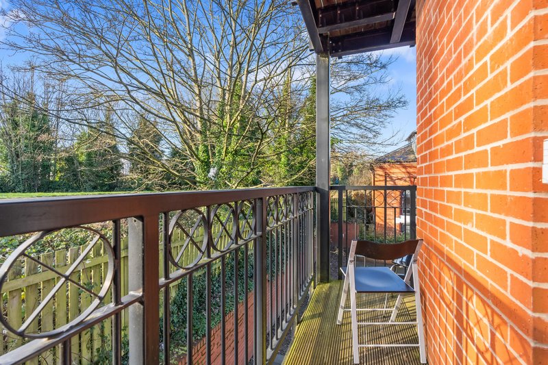 Brick building balcony with metal railing overlooking trees and surrounding landscape