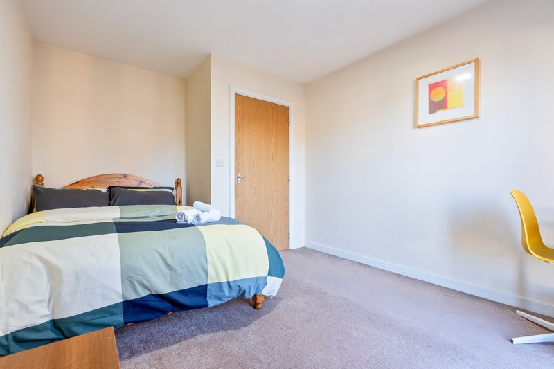 Bedroom with double bed, blue striped bedding, wooden door, and framed artwork on wall