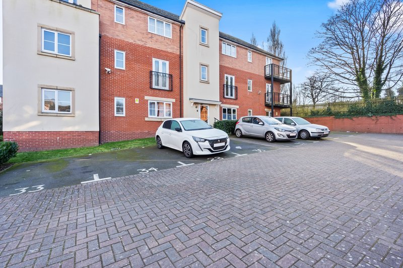 Modern apartment building with brick and render facade, parking area with three cars