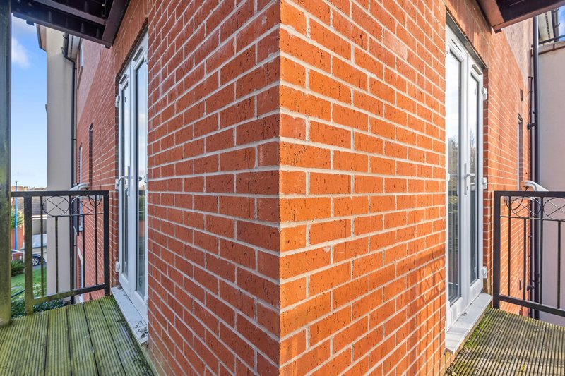 Exterior corner of red brick building with white-framed doors and metal railings