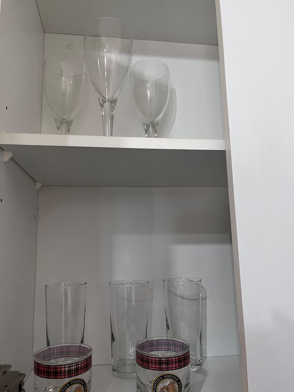 White shelving unit displaying clear drinking glasses and cups with plaid fabric accents