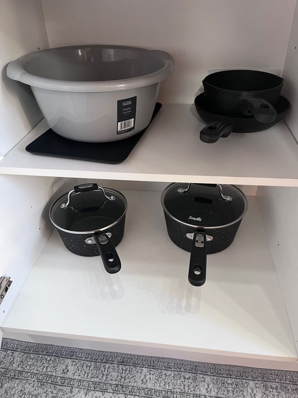 Kitchen shelf with various cooking pots and pans, including a white rice cooker and black cookware.