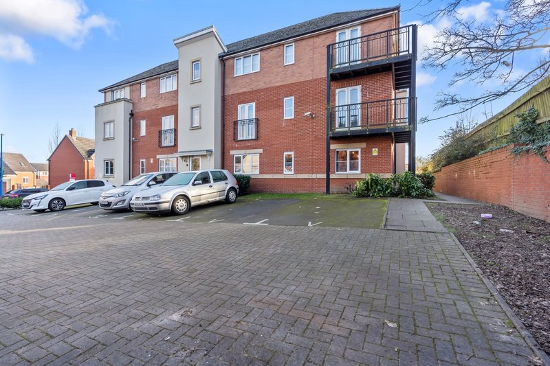 Modern apartment building with brick facade, parking area and landscaped grounds