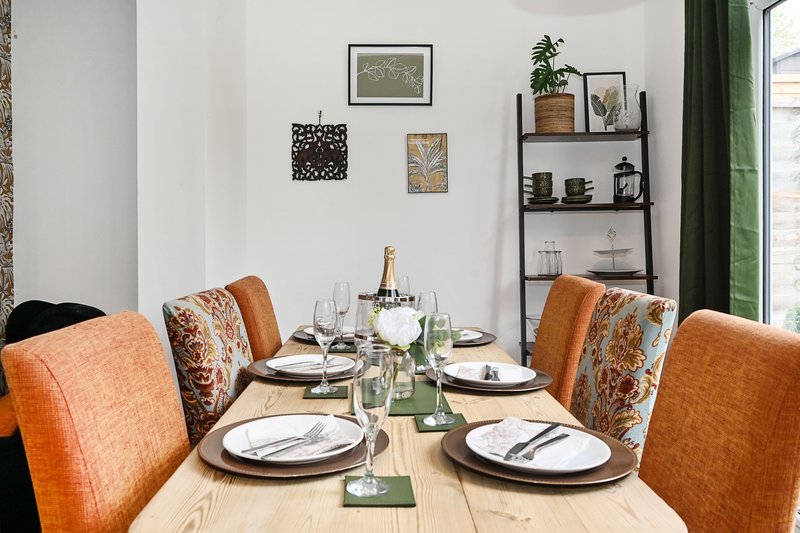 Modern dining room with wooden table, orange upholstered chairs, place settings, and wall art
