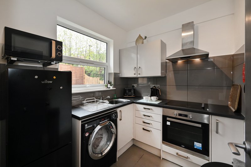Modern kitchen with black appliances, white cabinetry, washing machine and window view