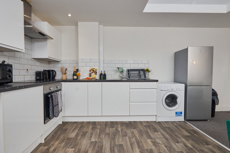 Modern kitchen with white cabinets, stainless steel appliances, wooden floor and subway tile backsplash