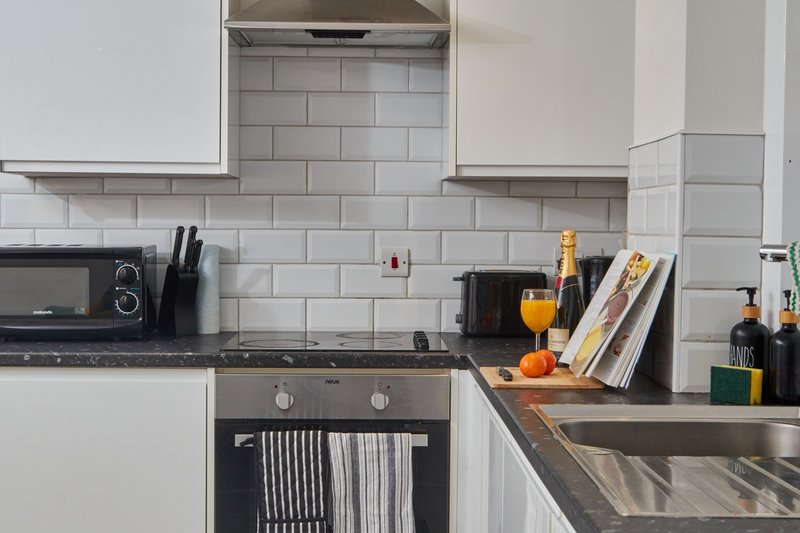 Modern kitchen with white subway tile backsplash, dark countertops, built-in oven and champagne bottle display