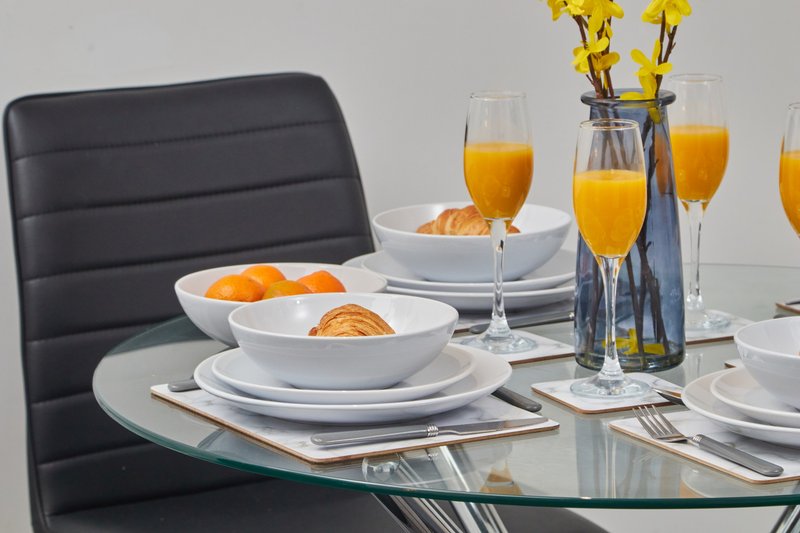 Dining table set with plates, glasses of orange juice, and yellow flowers in vase