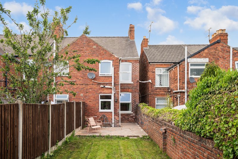Red brick terraced house with garden, patio area and wooden fence