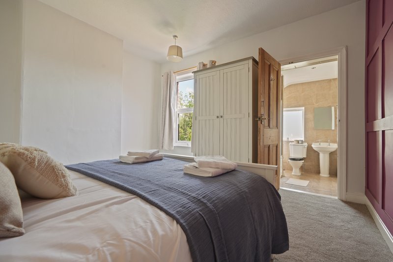 Bright bedroom with twin beds, ensuite bathroom visible, and garden view through window