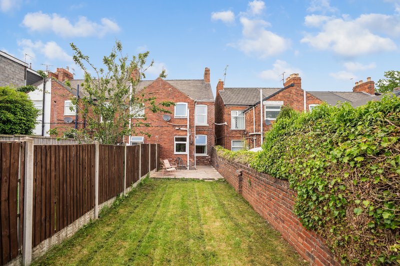Brick terraced house with rear garden, lawn, wooden fence and hedges