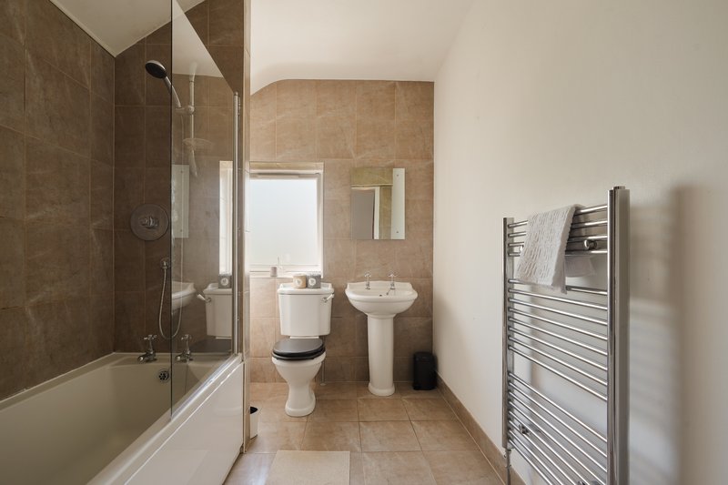 Bathroom with shower enclosure, pedestal sink, toilet, heated towel rail and tiled walls