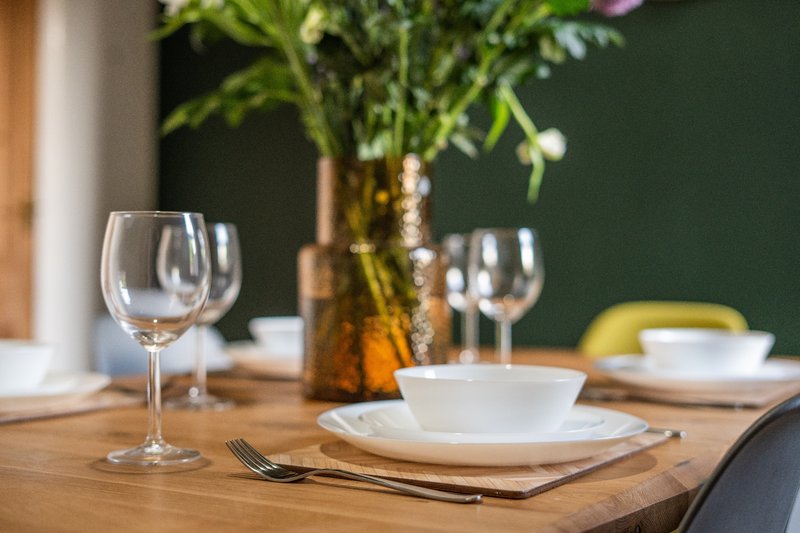 Dining table with place setting, wine glasses, and fresh flowers in vase