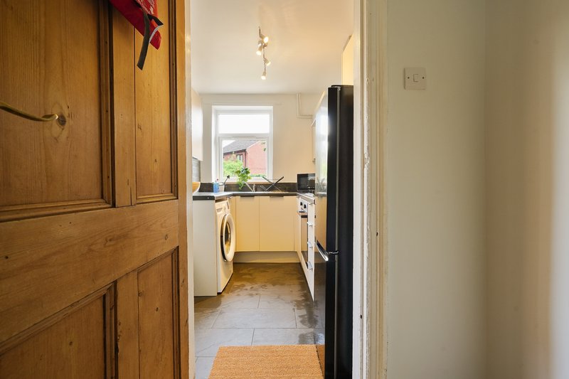 Kitchen viewed from hallway with washing machine, countertop, and window to garden