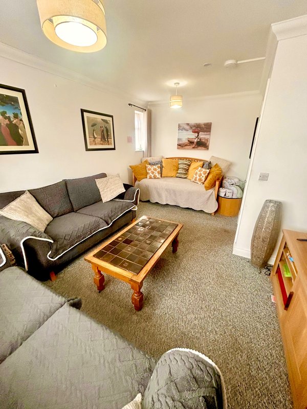 Bright living room with dark sofa, wooden coffee table, yellow cushions and wall art