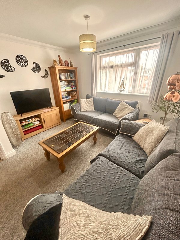 Bright living room with grey sofa, wooden TV unit, coffee table, and decorative wall plates