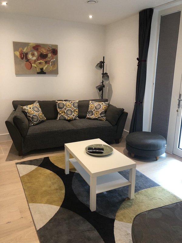 Living room with black sofa, white coffee table, patterned cushions and wall art