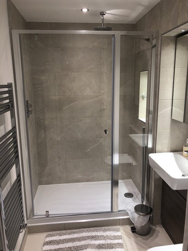 Modern bathroom with walk-in shower enclosure, white basin, heated towel rail and tiled walls
