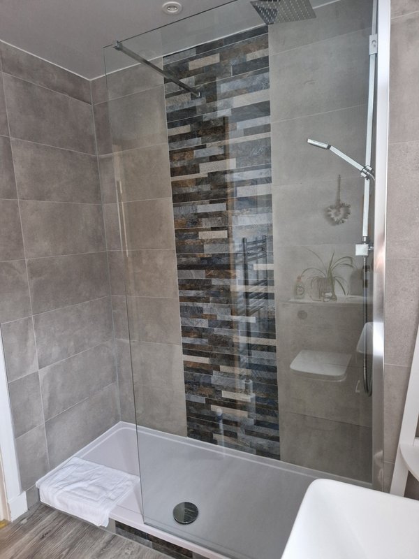 Modern bathroom with walk-in shower, glass enclosure, and tiled accent wall
