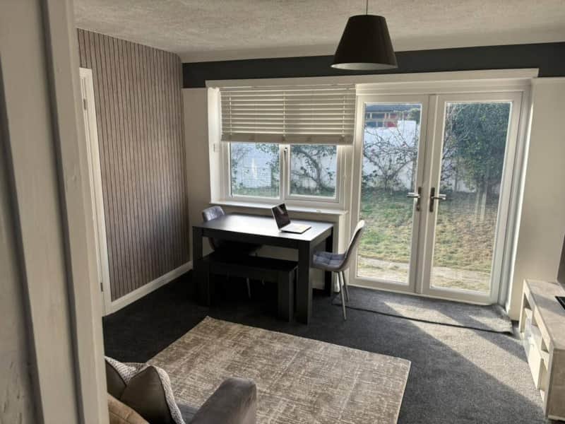 Modern home office with black desk, chair, large glass doors overlooking garden