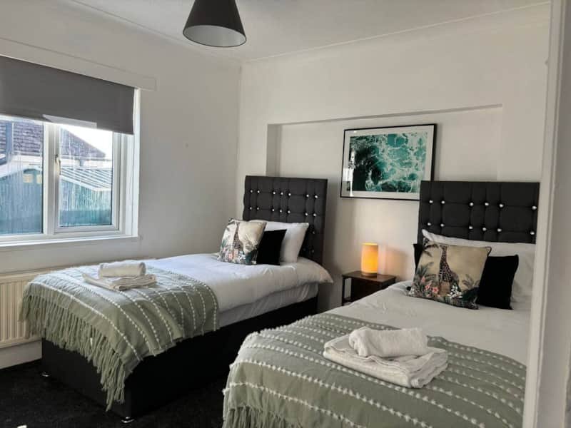 Twin bedroom with two single beds, black headboards, bedside tables, and wall mirror