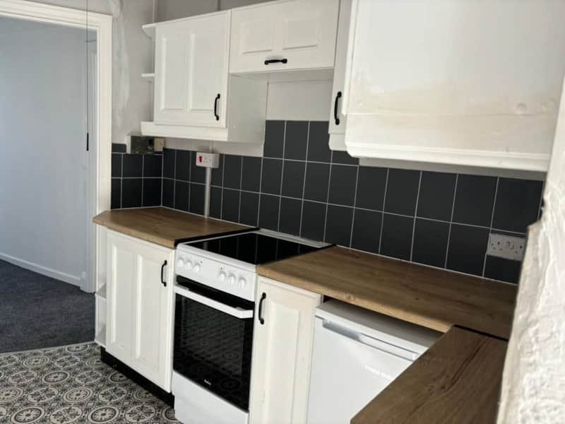 Modern kitchen with white cabinets, black tile backsplash, wooden countertops and integrated appliances