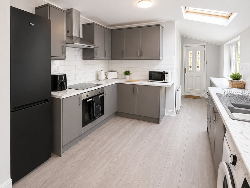 Modern kitchen with gray cabinets, white subway tile backsplash, black appliances and light wood flooring