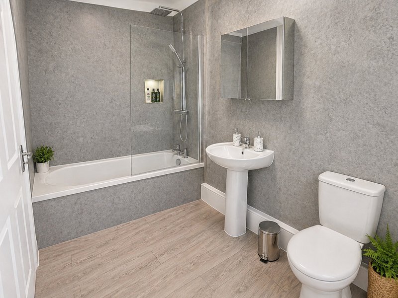 Modern bathroom with bathtub, pedestal sink, toilet, mirror cabinet and wood-effect flooring