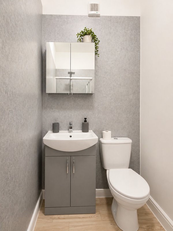 Compact bathroom with gray vanity, round white sink, mirrored cabinet, and white toilet