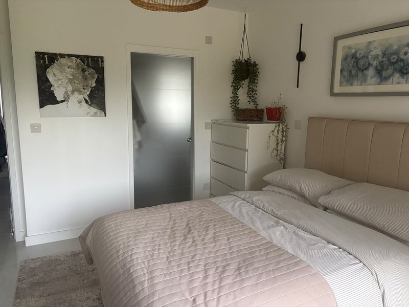 Modern bedroom with double bed, beige headboard, bedside table and wall art
