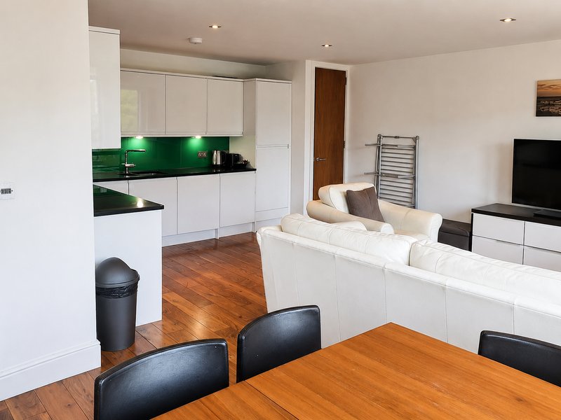 Open-plan living space with kitchen, dining table, and seating area with TV