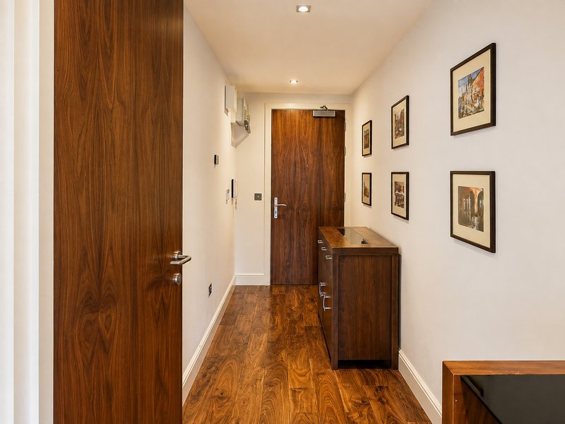 Hallway with wooden doors, hardwood flooring, framed artwork on walls
