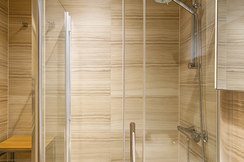 Modern shower enclosure with glass doors, wooden tile walls and grab bar