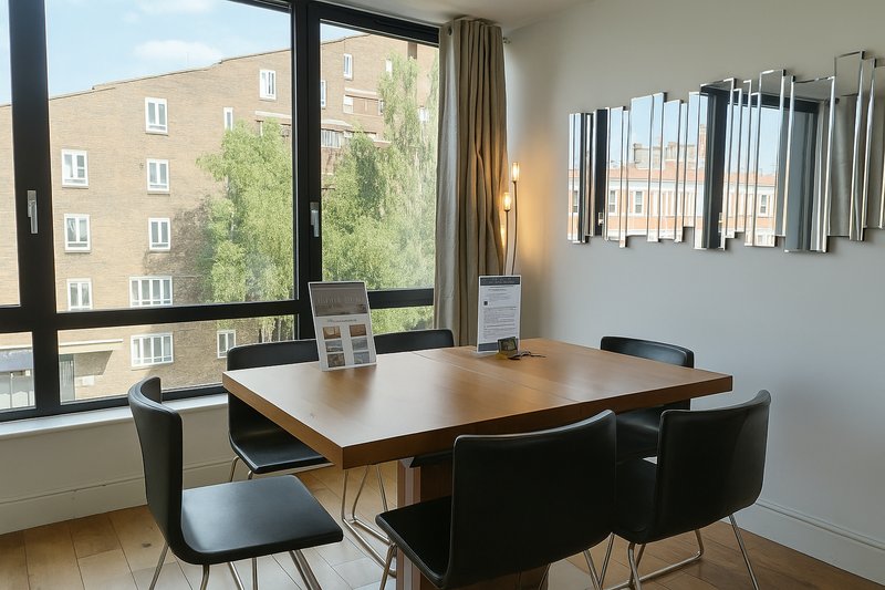 Modern dining area with wooden table, black chairs, large windows overlooking residential street