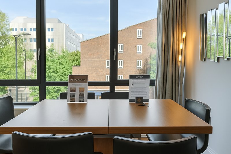 Modern dining table with black chairs, large windows overlooking urban streetscape and buildings