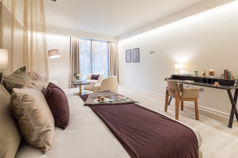Modern bedroom with double bed, burgundy throw, desk area and large window with curtains